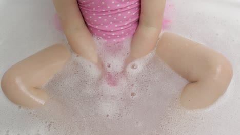 hands of girl puts bath bomb to water. ball of bath salt dissolves in water