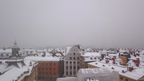 Pase-De-Baja-Altitud-Con-Drones-Sobre-El-Distrito-De-Gamla-Stan-En-Estocolmo-Suecia-En-Un-Día-De-Niebla-Nevada-Llegando-A-La-Isla-De-Skeppholmen