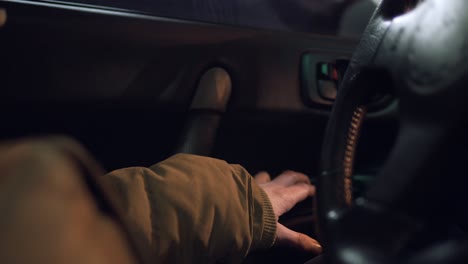 man hand pressing a button to close the window of a car.