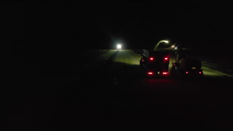 following aerial footage of chopper farm vehicles working by spotlight at night