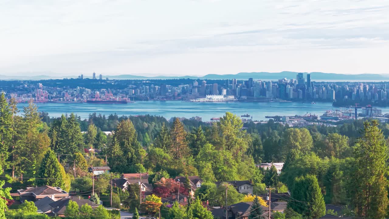 Ampia veduta diurna dello skyline della città di Vancouver e del porto, vista da una collina residenziale boscosa, con sempreverdi e case di quartiere in primo piano