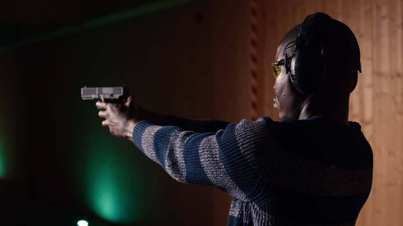 человек на стрельбище пробует новую модель пистолета, прежде чем согласиться на покупку.