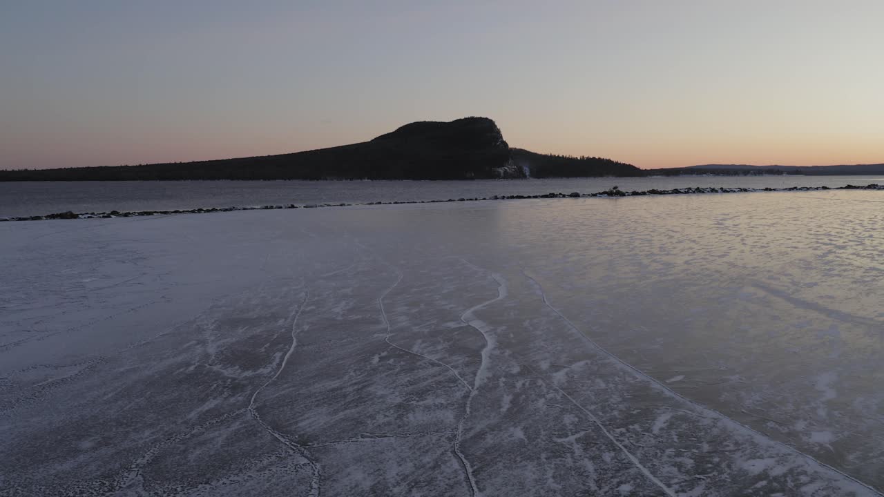 hielo protegido por rompeolas en un lago al amanecer con montaña a distancia aérea