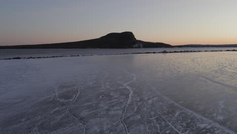 Ice-protected-by-breakwater-on-a-lake-at-dawn-with-mountain-in-distance-AERIAL