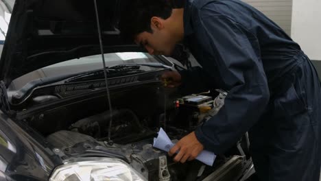 handsome mechanic checking oil in a car engine