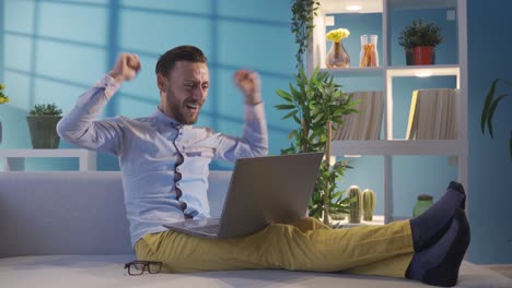 hombre de negocios exitoso guapo y carismático mirando la computadora portátil y regocijándose por ganar. hombre sonriente regocijándose.