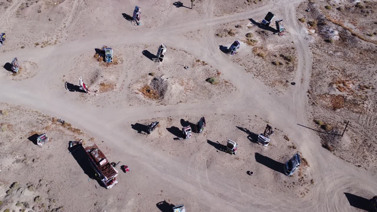 Pan shot from a drone of a car graveyard in a desert.