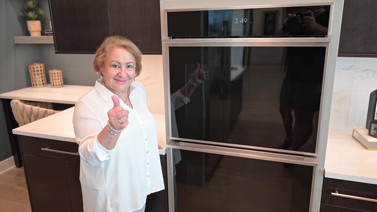 Donna che ama la sua nuova installazione di forno doppio dopo una ristrutturazione della cucina