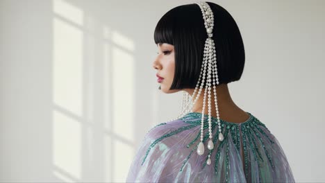 a captivating portrait of elegance: a model with an artistic bob hairstyle and glamorous beaded accessory poses gracefully against a light-filled background