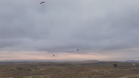 Temecula-Balloon-and-Wine-Festival-Drone-Footage-Four-Hot-Air-Balloons-With-Two-Paragliders-One-Flies-Out-of-Frame