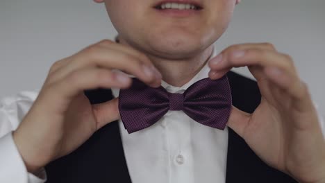 Groom-adjusts-bow-tie.-Preparing-to-go-to-the-bride.-Wedding-day