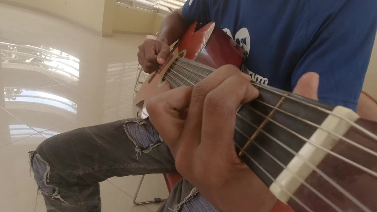 toma fpv de una guitarra acústica tocada por un niño, con los dedos en la toma