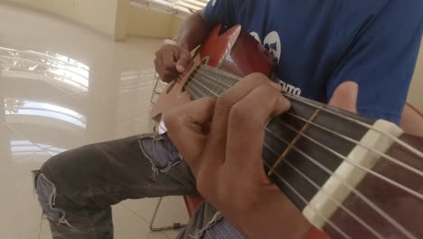 fpv shot of an acoustic guitar being played by a boy, fingers in shot