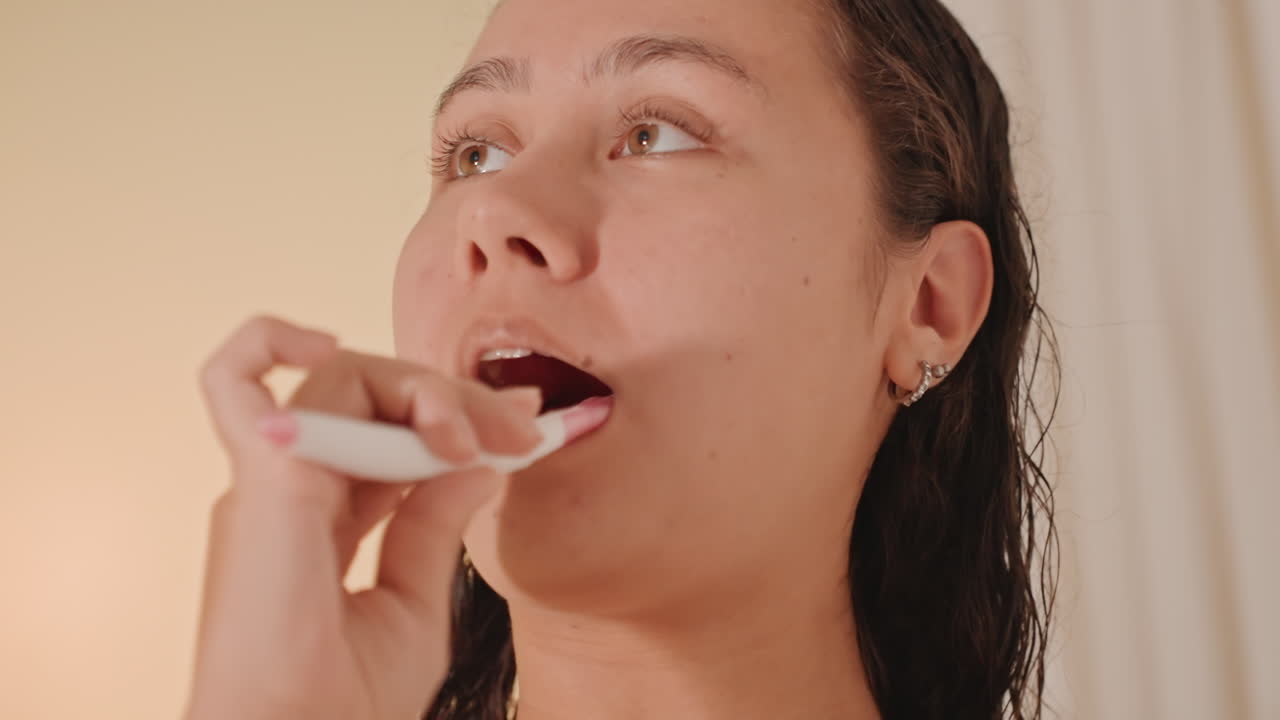 Closeup of guest cleaning teeth peacefully. Comfortable hotel setting with warm lighting and oral hygiene. Guest calmly performing personal dental care in cozy bathroom with gentle illumination