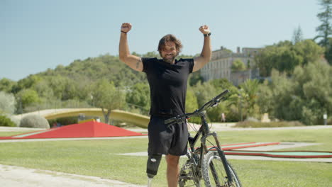 un ciclista feliz con una pierna biónica levantando las manos en señal de victoria