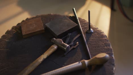 Close-up-of-diverse-jeweller-tools-lying-on-desk-in-workshop