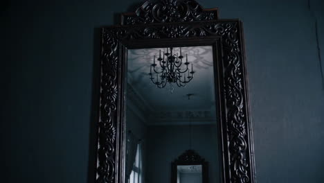 ornate mirror reflecting a chandelier in a dark room