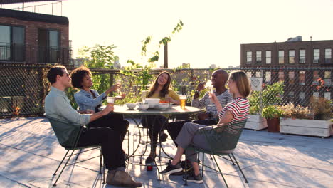 Amigos-Bebiendo-En-Una-Mesa-En-La-Terraza-De-La-Azotea,-De-Longitud-Completa