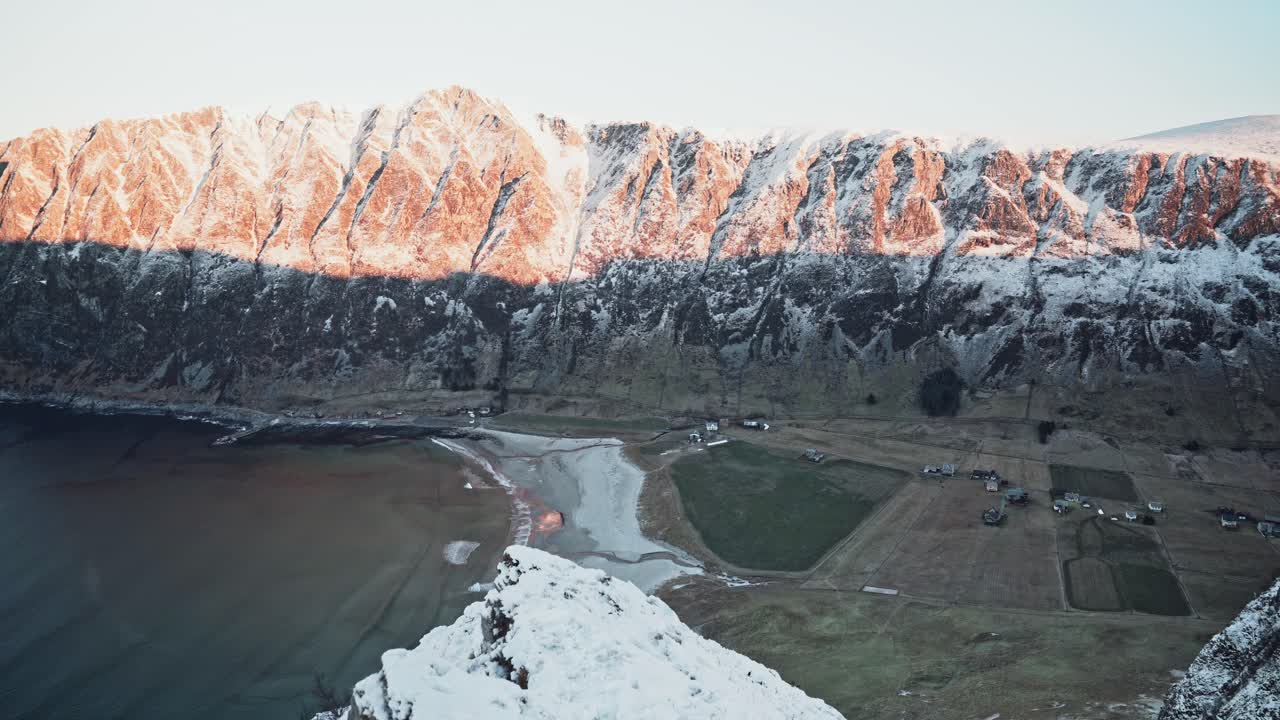 hermoso amanecer tomado desde el borde de una montaña cubierta de nieve, con vistas al océano y al terreno montañoso, hoddevik, noruega