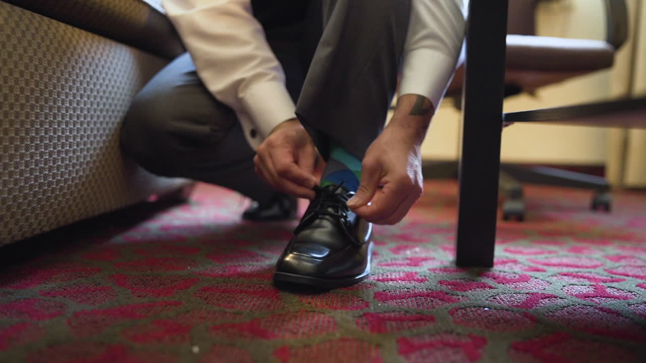 결혼식 날 호텔 방에서 신랑이 신발을 묶고 있다