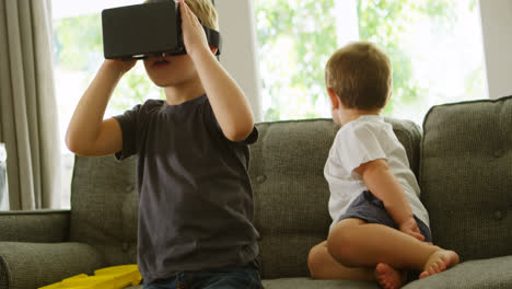 Junge-Sitzt-Auf-Dem-Sofa,-Während-Sein-Bruder-Ein-Virtual-Reality-Headset-4K-Verwendet