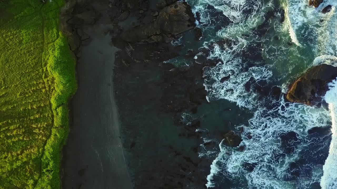 Flying above the rugged Tanah Lot coastline as it transitions into verdant pasture. The shot captures coastal drama, natural textures, and the peaceful blend of sea and land.