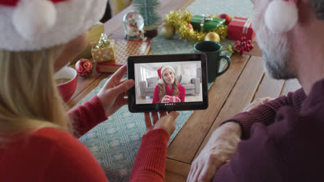 Pareja-Caucásica-Con-Sombreros-De-Santa-Usando-Tableta-Para-Videollamada-Navideña-Con-Mujer-En-Pantalla