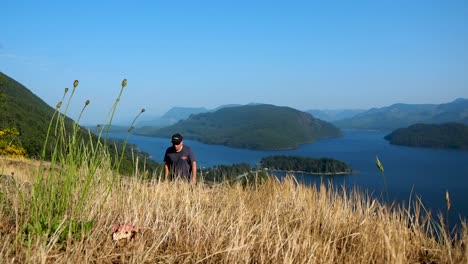 man walking up mountain with lake and mountain in background
