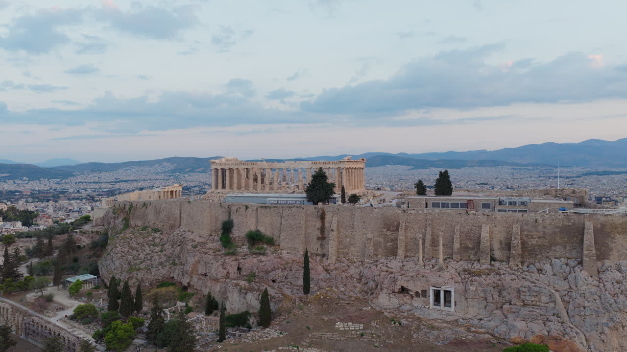 Drone circles around Acropolis of Athens and the Parthenon ruins at hilltop during sunrise. Athens