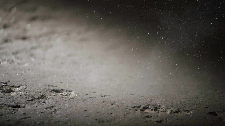 Aufwirbelnde, flüchtige Störung bewegt Schleier über strukturiertem, staubigem Boden aus niedriger Perspektive, Bokeh erzeugend.