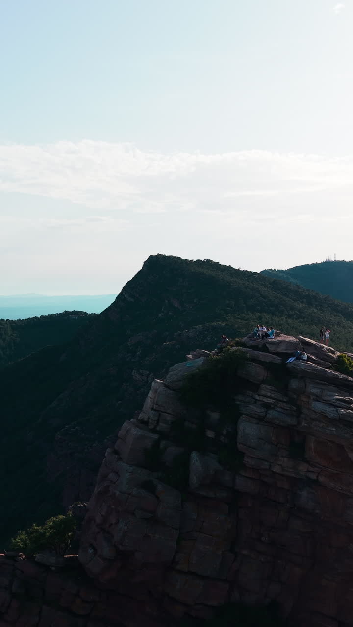 Aerial View of People on a Rocky Mountain Cliff with Scenic Landscape