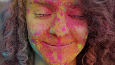 close-up portrait of cheerful mixed race girl dirty with bright gulal paint smiling outdoors