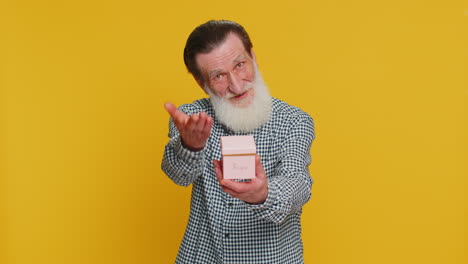 smiling senior man presenting jewelry gift present box stretches out hands promotion discount sale