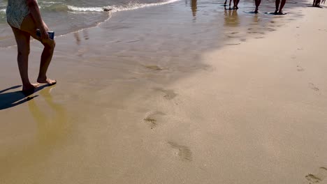 european woman feet walking on sandy ocean beach at exotic island along sea water waves in guincho, portugal