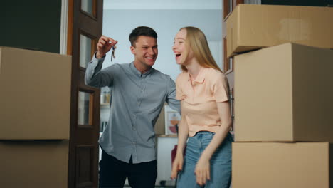 woman rejoicing moving new home hugging husband. man making surprise to wife.