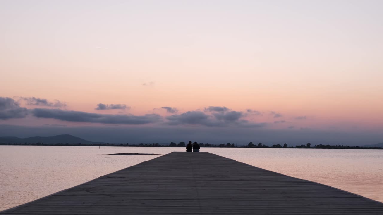 Anonymous persons sitting on end of pier