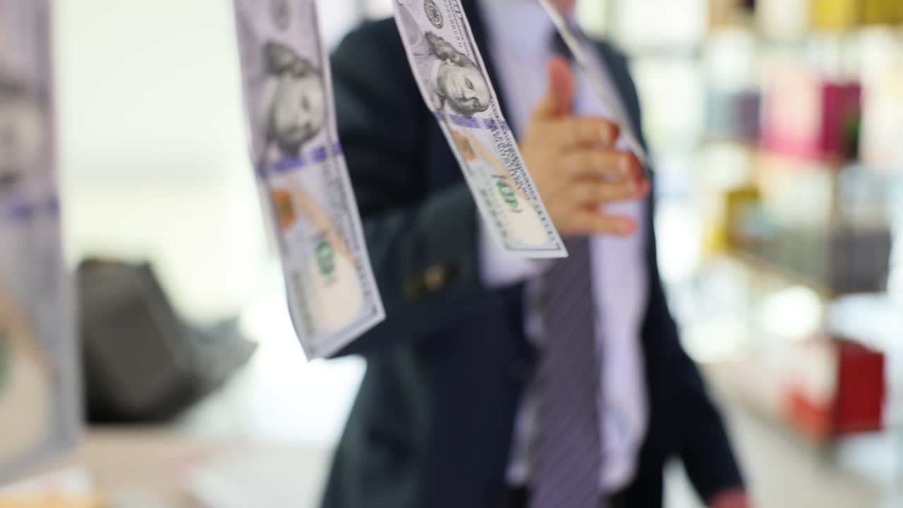 Person holding a hundred dollar bill hanging on a clothesline, symbolizing money laundering