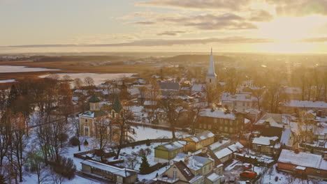 Cinematic-view-of-an-Orthodox-and-Lutheran-Church-in-golden-winter-sunlight,-Sunset-aerial,-Christianity-concept