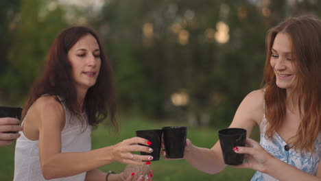 a group of young women in nature in an open area at sunset in the evening are sculpting from clay using tools decorating products communicating sharing impressions rejoicing in the results.