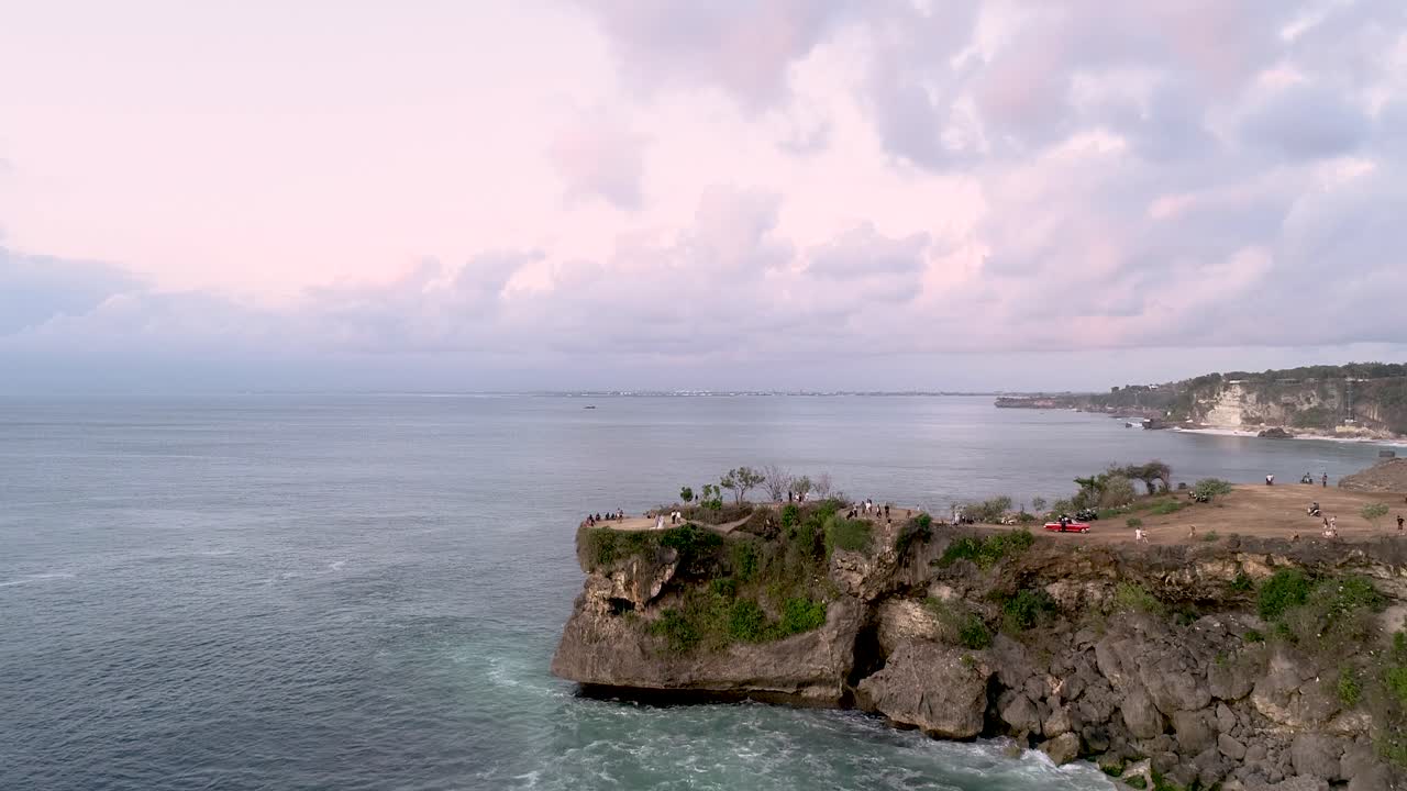Aerial Closing Green Rock Cape With Waves and Cloudy Day at Balangan Beach Bali Indonesia Asia