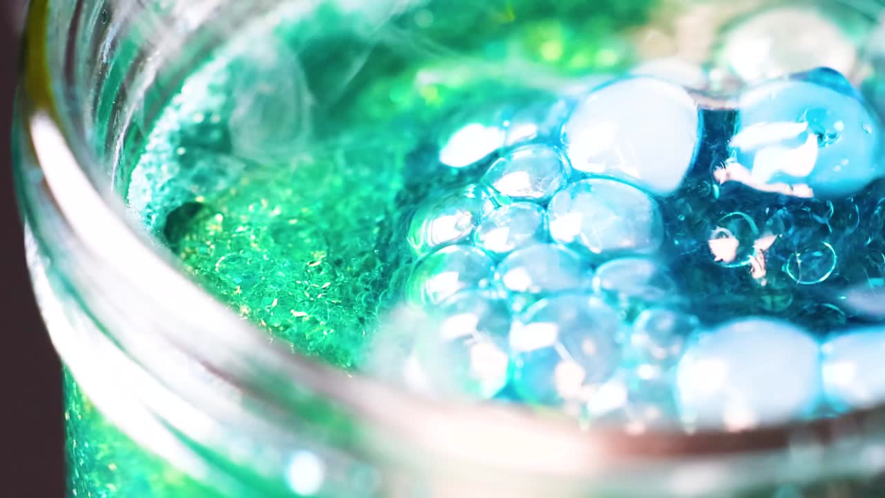 A mesmerizing close-up of blue and green bubbles forming and interacting in a glass jar.