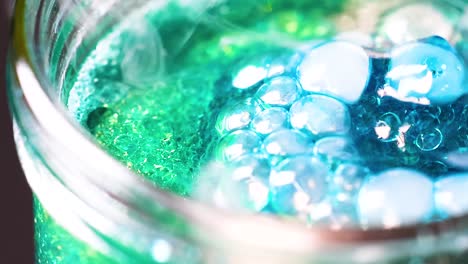 a mesmerizing close-up of blue and green bubbles forming and interacting in a glass jar.