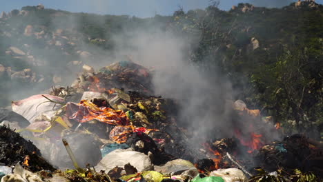 close up shot of rubbish heap burning outdoors at asian landfill during sunlight - air pollution and contamination