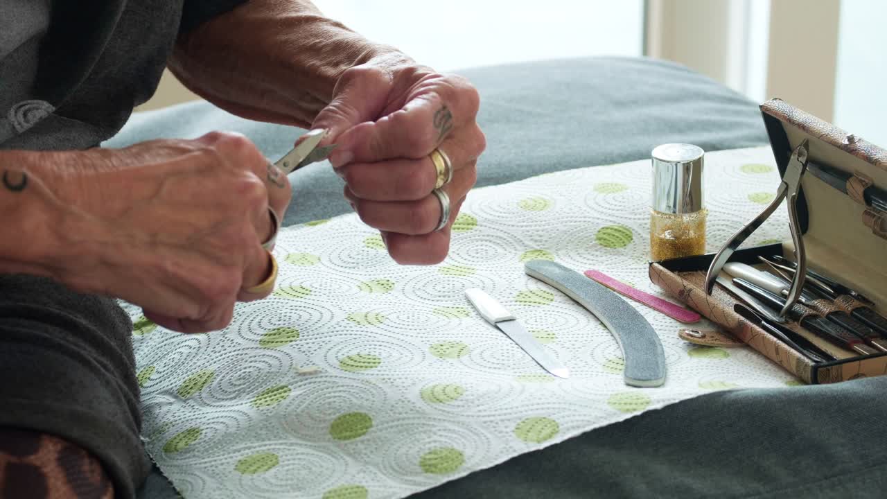 Detail shot of a woman filing her nails on a soft surface. Clean and bright aesthetic focusing on hand grooming and personal beauty care for lifestyle and wellness commercial use