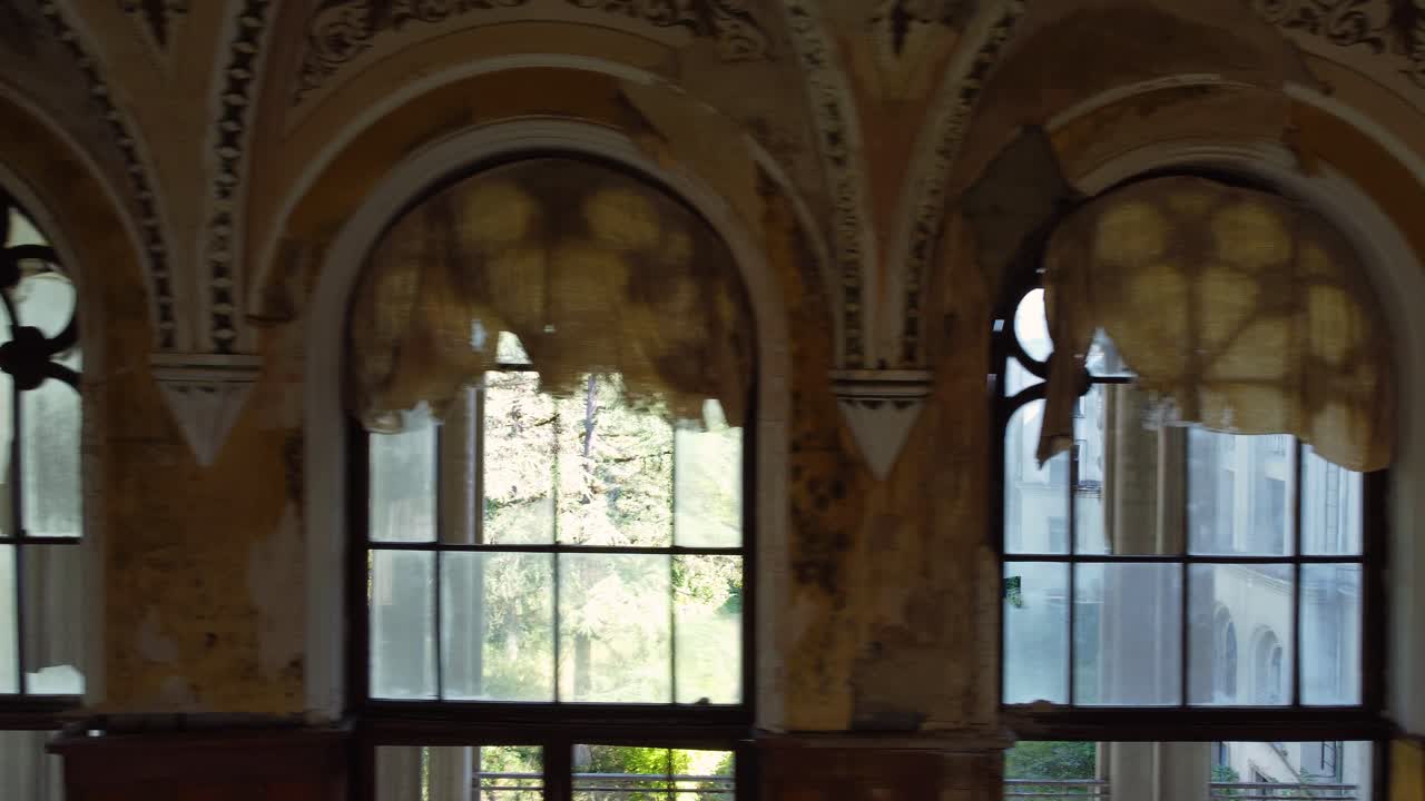 Interior hall of abandoned Tskaltubo spa with tall arched windows and faded elegant details