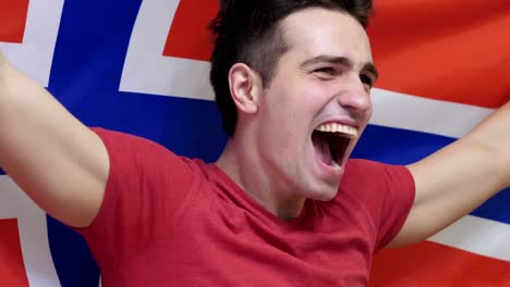 joven noruego celebrando mientras sostiene la bandera de noruega en cámara lenta