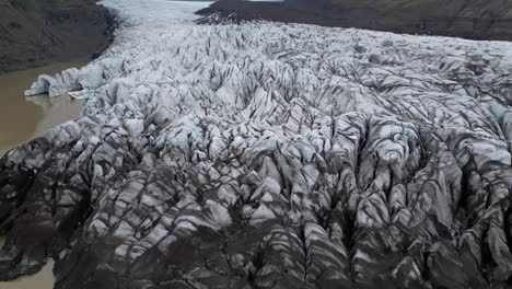 Aerial-view-from-Svínafellsjökull-glacier-in-Iceland,-located-between-two-steep-mountains-and-different-types-of-ice-covering-the-landscape