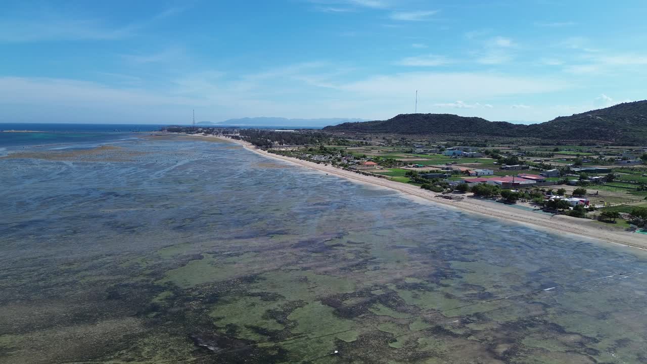 Drone panning left showing the vast My Hoa Lagoon coastline with shallow waters and green surroundings under daylight.