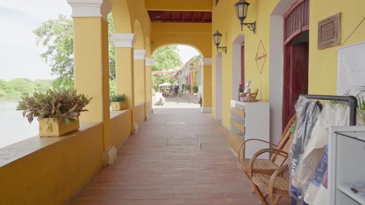 Plano subjetivo moviéndose lentamente a través de una galería colonial amarilla junto a un río en Mompox