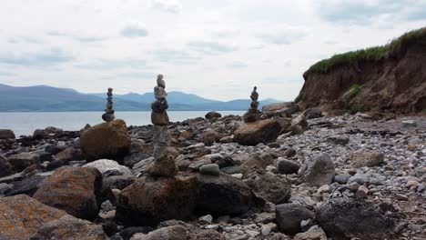 Balanced-spirituality-meditation-pebbles-piled-on-alien-rocky-mountain-range-beach-coastline-dolly-right